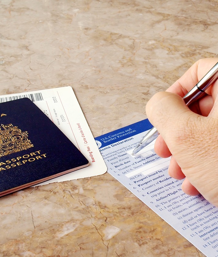 a person fills out border and customs information with a passport nearby
